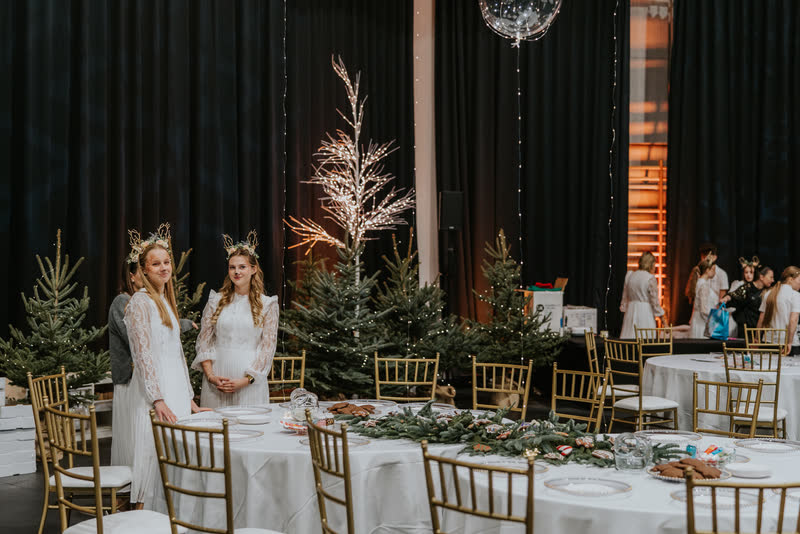 Sala eventu mikołajkowego z udekorowanymi stołami i choinkami