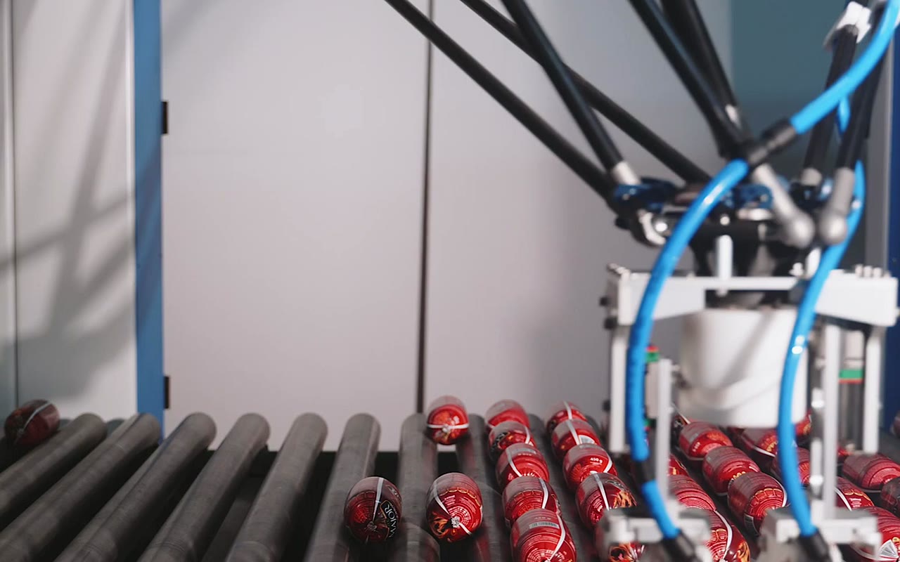 Robot pakujący nad taśmą produkcyjną — kadr z filmu dla firmy Maluka